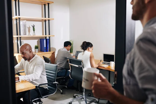 Empresario Con Taza Café Entrando Habitación Con Colegas Ocupados Con — Foto de Stock