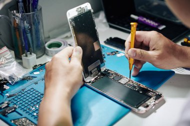 Tamirci akıllı telefon ekranını kaldırıyor ve Sim kart tepsisini güvene alıyor