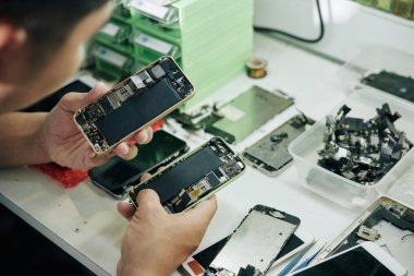 Onarmadan önce akıllı telefonları inceleyen tamircinin yakın plan görüntüsü