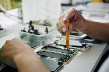 Akıllı telefon pilini çıkarırken pentalob tornavida kullanan tamircinin elleri