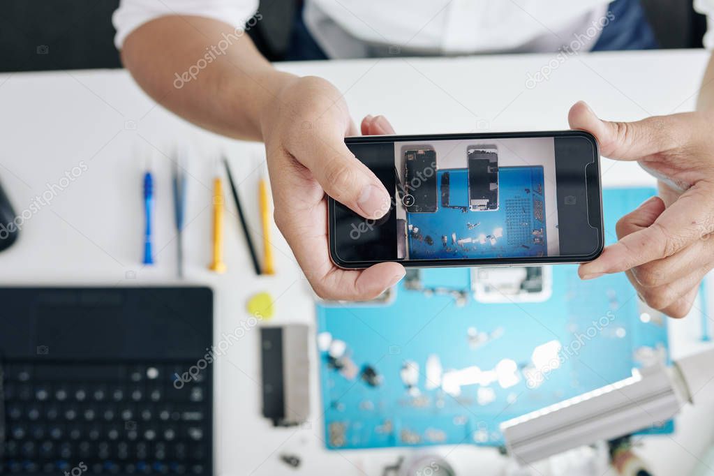 Photo of disassembled smartphone on screen of phone in hands of repairman