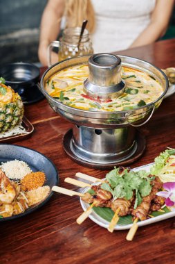 Baharatlı kalamar çorbası, metal tencerede ve kafeteryada çeşitli deniz ürünleri atıştırmalıkları.