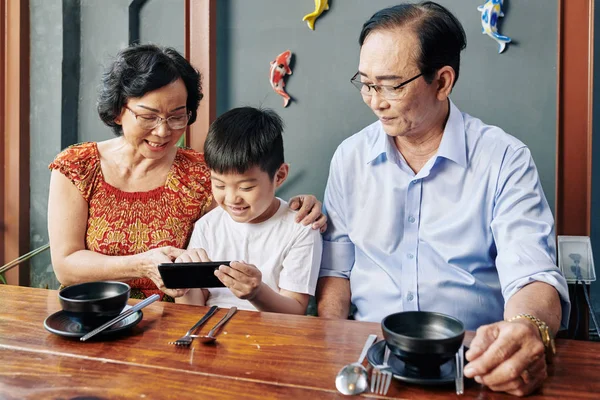 Happy Asian Grandparents Grandchild Sitting Cafe Table Using Mobile Application — Stok fotoğraf