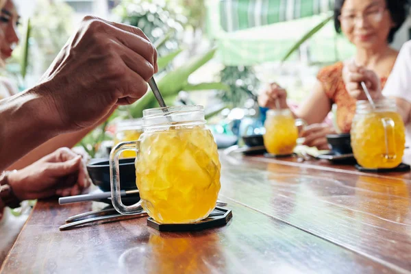 咖啡店访客的手坐在桌旁 搅拌着甜菠萝鸡尾酒 — 图库照片