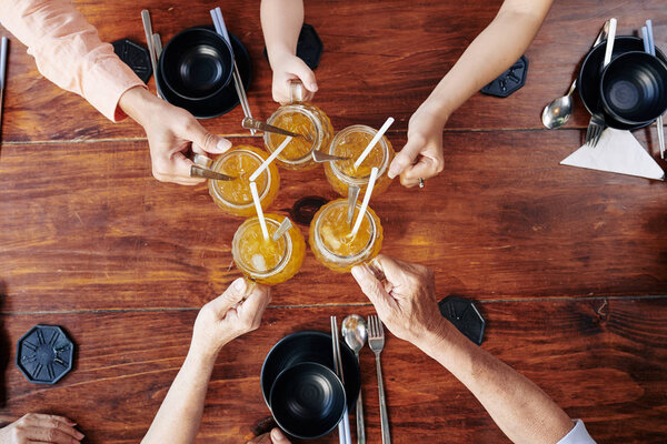 Руки семьи звон стаканов с вкусным холодным фруктовым коктейлем, вид сверху
