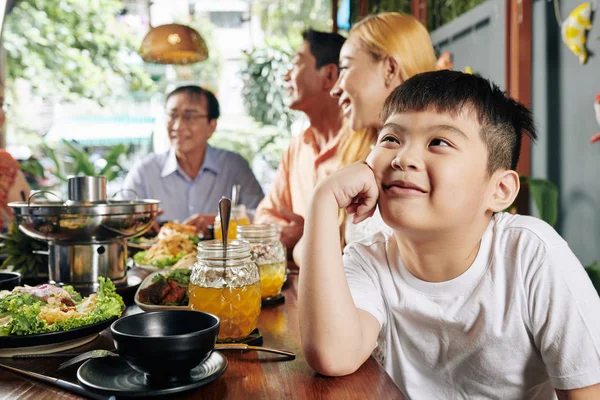 家族のお祝いの間に夕食のテーブルに座っているとき 愛らしいベトナムの少年は笑って 見上げ 夢を見て — ストック写真