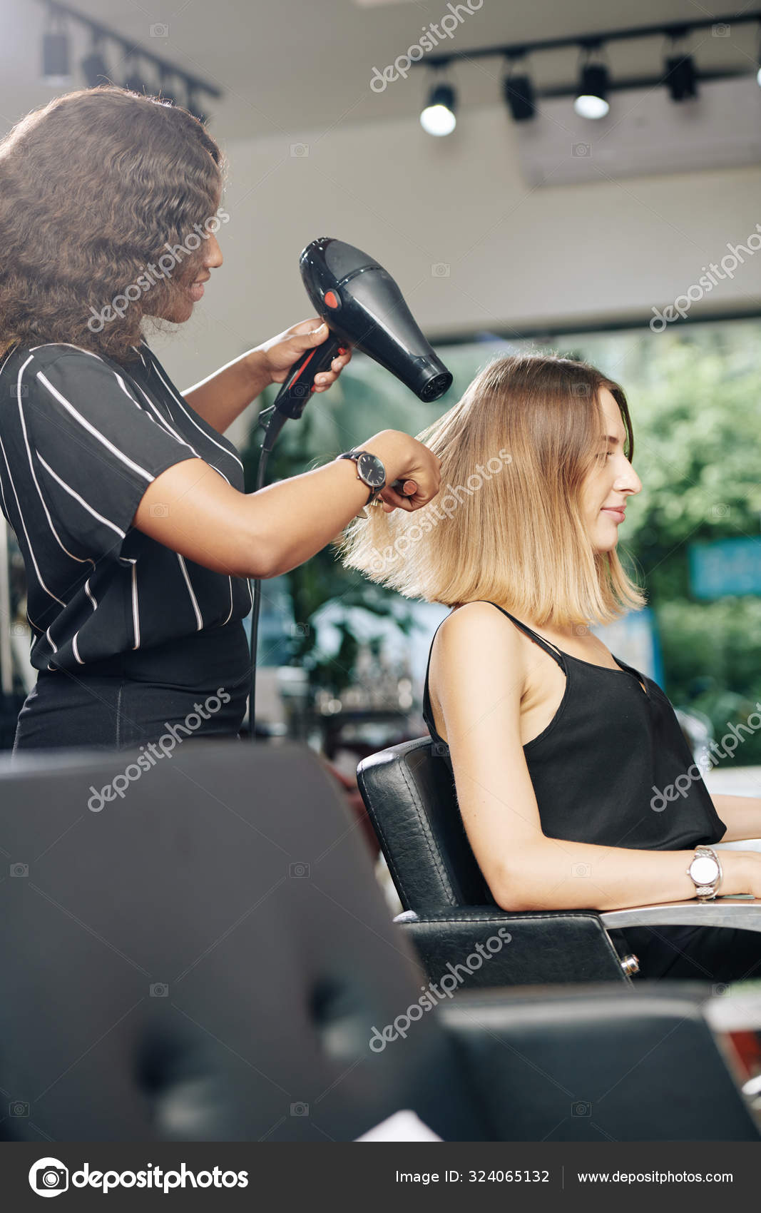 mulher jovem e bonita usando secador de cabelo no salão de