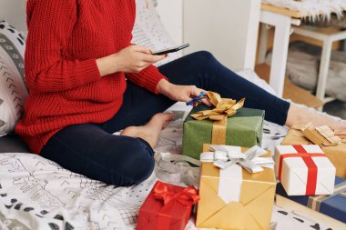 Cropped image of young woman taking photo for social media when wrapping Christmas presents