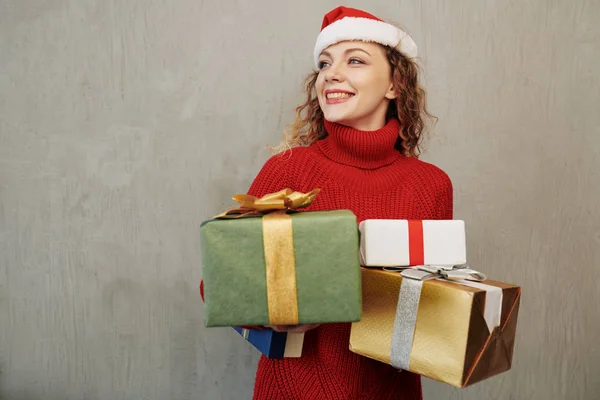 快乐的年轻白人女人戴着圣诞礼帽 手里拿着许多圣诞礼物 — 图库照片