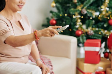 Yaşlı bir kadının televizyon kanallarını değiştirip Noel arifesinde izlemek için en iyi eğlenceyi aradığı görüntüler.