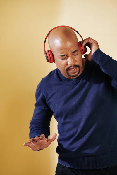 Middle-aged fit man closing eyes when dancing to the music in his headphones