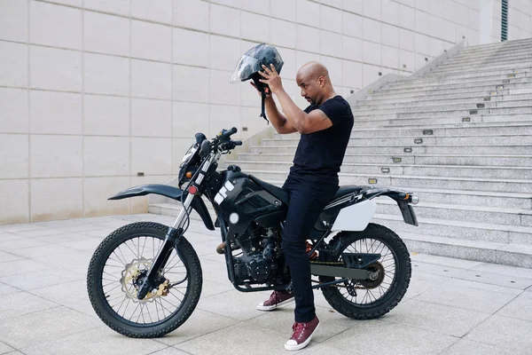 Schöner Muskulöser Mann Sitzt Auf Motorrad Und Setzt Helm Auf — Stockfoto
