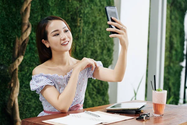 Piękne Uśmiechnięty Młody Azji Kobieta Pozowanie Dla Selfie Podczas Siedzi — Zdjęcie stockowe