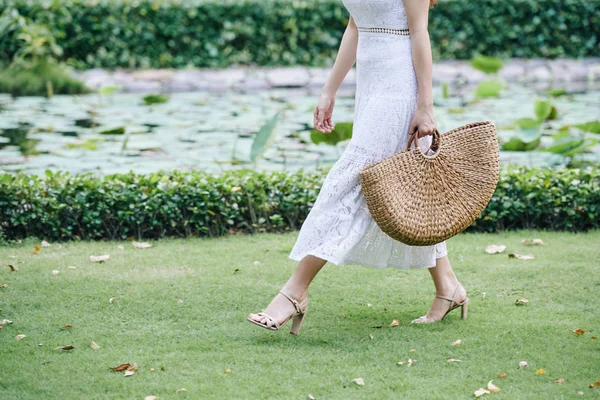 夏の日にわら袋で公園を歩くレースドレスの若い女性の作物のイメージ — ストック写真