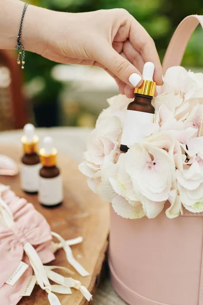 Mano Mujer Tomando Botella Aceite Esencial Emulsión Cesta Flores Frescas —  Fotos de Stock