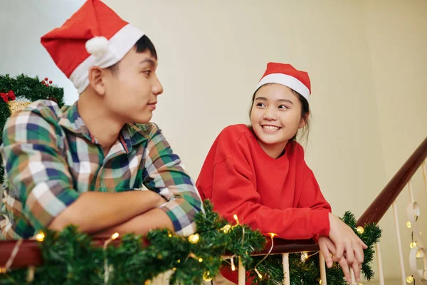 Glimlachende Tiener Broer Zus Santa Hoeden Leunend Leuning Chatten Kerstavond — Stockfoto