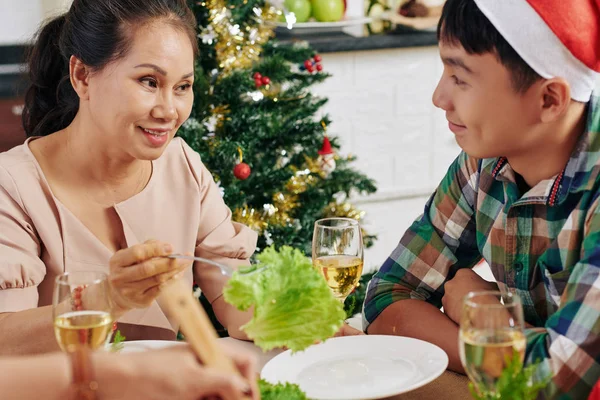 Senior Asian woman talking to her teenage grandson at Christmas dinner