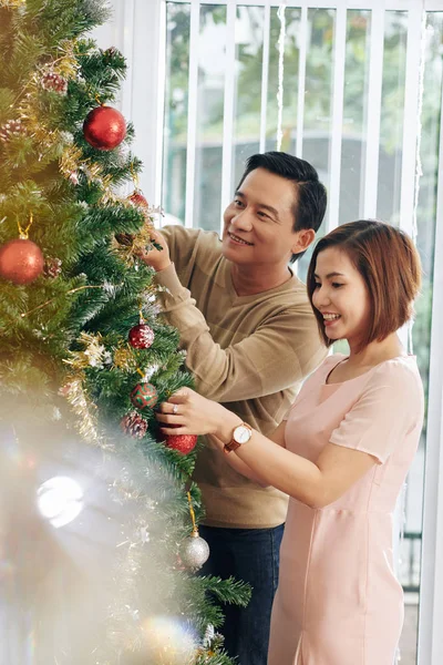 Cheerful Middle Aged Vietnamese Couple Enjoying Decorating Tree Christmas Baubles — 스톡 사진