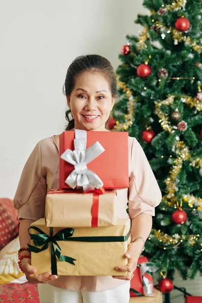 幸せなシニアベトナム人女性の肖像装飾されたクリスマスプレゼントのスタック — ストック写真