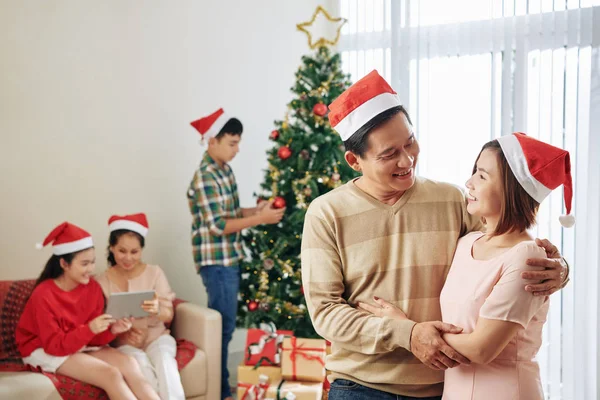 笑顔の中年の夫と妻抱擁し クリスマスのお祝いのために彼らの家族が準備するとき お互いを見て — ストック写真