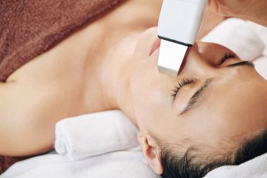 Güzellik salonunda ultrason yaptıran genç bir kadının yakın plan görüntüsü.