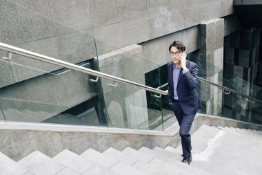 Yeraltı geçidinde yürürken ciddi bir işletme yöneticisi telefonda konuşuyor.