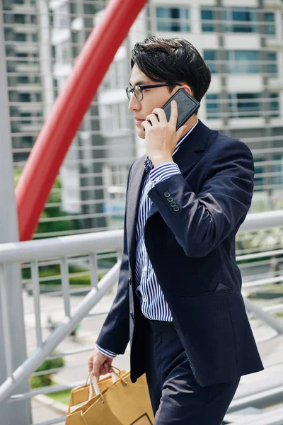 Молодой Уверенный Предприниматель Бумажными Пакетами Гуляющий Улице Разговаривающий Телефону — стоковое фото