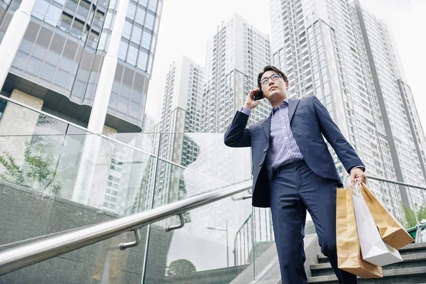Komoly Ázsiai Férfi Szemüvegben Papírzacskókkal Kezében Amikor Lejön Lépcsőn Telefonon — Stock Fotó