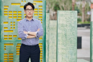 Sokakta dikilip kameraya bakan Asyalı genç yazılım geliştiricisinin portresi