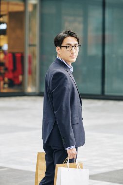 Yakışıklı Vietnamlı adamın portresi. Alışveriş merkezinden kağıt torbalarla çıkıyor.