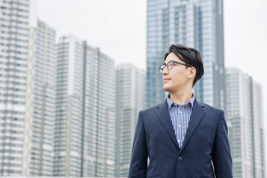 Kendine güvenen hırslı iş adamı dışarıda duruyor ve gökdelenleri olan yeni bir bölgeye bakıyor.