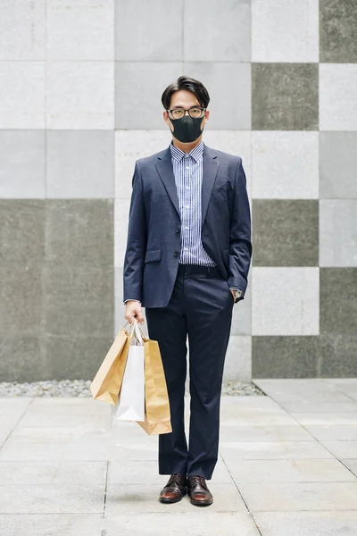 站在火车站 头戴面具 提购物袋的亚洲企业家全长肖像 — 图库照片