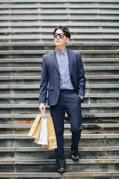 Fashionable attractive young man walking down the stairs after shopping