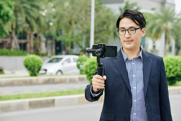 Hombre Asiático Gafas Haciendo Vídeo Teléfono Inteligente Conectado Monópodo —  Fotos de Stock