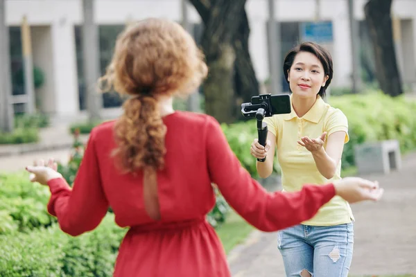年轻的亚洲女人手握智能手机 手握一脚架 向女性博主展示她可以继续用相机交谈 — 图库照片