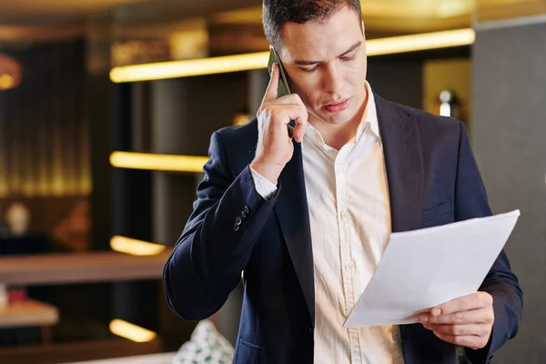 Seriöser Junger Gutaussehender Unternehmer Telefoniert Beim Lesen Des Berichts — Stockfoto