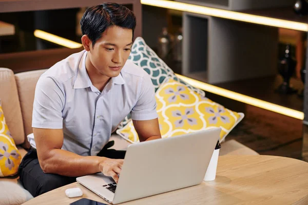 年轻而严肃的越南商人每天都在咖啡店里工作 他一边在键盘上打字一边看电脑屏幕 — 图库照片