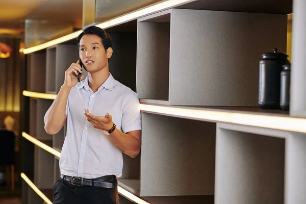 Jonge Vietnamese Ondernemer Leunend Planken Unit Praten Telefoon Met Collega — Stockfoto