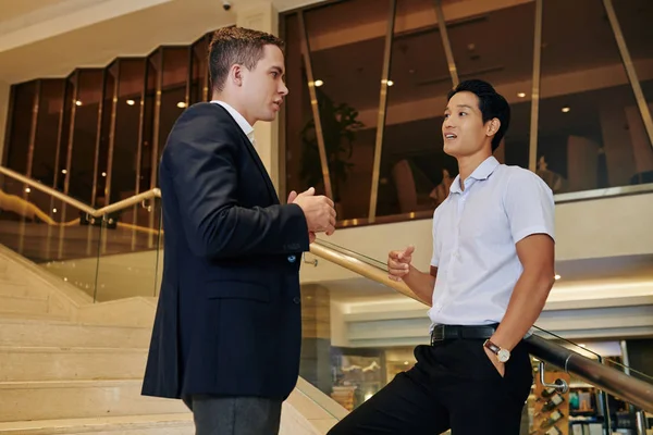 オフィスビルの階段で彼に会うときに同僚と話すハンサムな自信のあるベトナムのビジネスマン — ストック写真