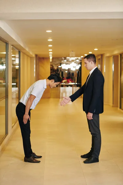 Caucasian Businessman Outstretching Arm Handshake His Asian Colleague Bending Forward — Stock Photo, Image
