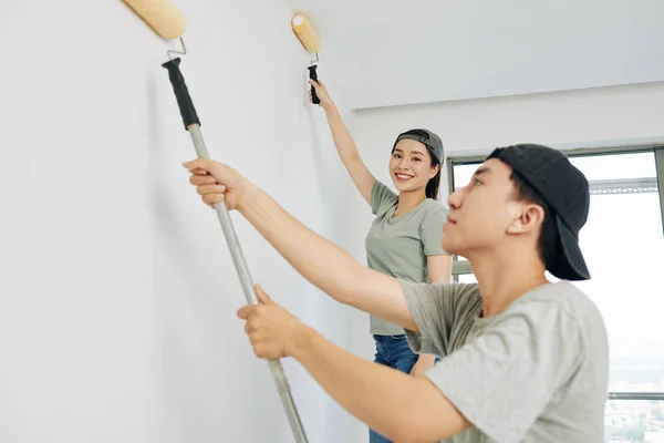 Pretty young smiling house painter working in house with her male colleague and looking at camera