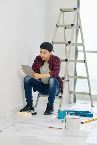 Handsome Young Vietnamese Man Sitting Ladder Reading Instruction How Paint — 스톡 사진