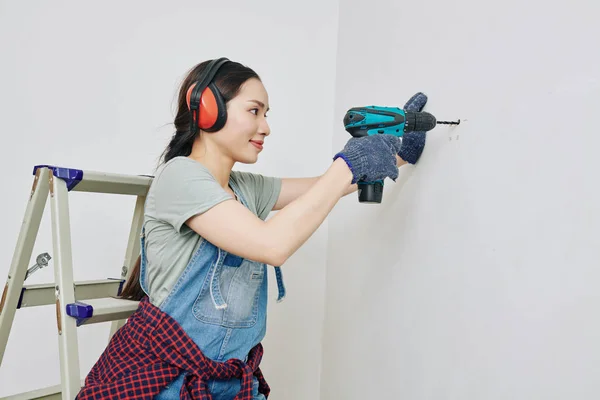 Sonriente Mujer Joven Bonita Orejeras Protectoras Perforando Pared Apartamento — Foto de Stock