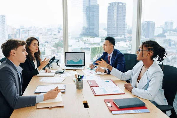 大事務所のテーブルに座って営業報告と会議での計画を議論する多民族ビジネスチーム — ストック写真