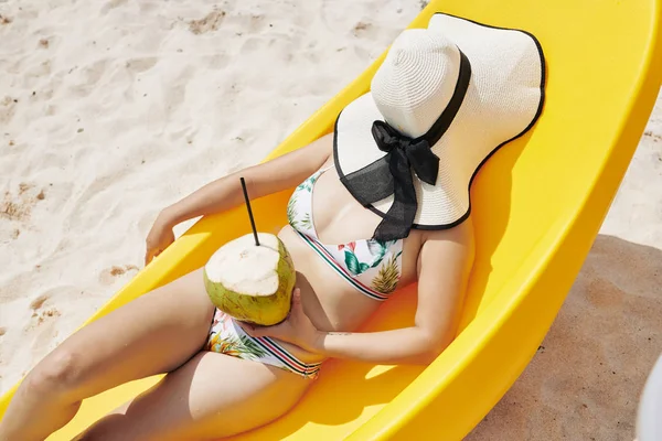 Młoda Kobieta Bikini Leżąca Poczekalni Słomkowym Kapeluszem Twarzy Koktajlem Kokosowym — Zdjęcie stockowe