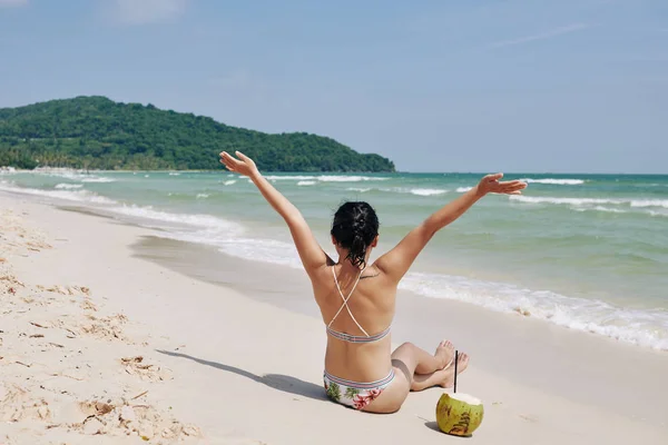 若い女性が腕を上げて 白い砂ときれいな海とビーチで彼女の偉大な休暇を祝う — ストック写真