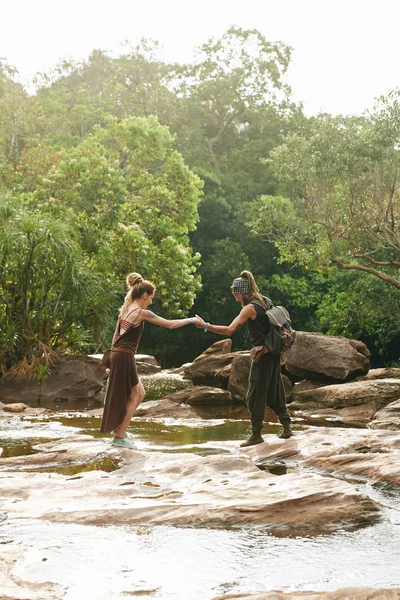 Mężczyzna Podając Rękę Dziewczynie Gdy Przekraczają Rzekę Podczas Wędrówki Lesie — Zdjęcie stockowe
