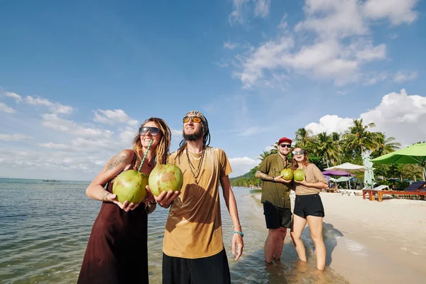 幸福的年轻夫妇戴着太阳镜 喝着新鲜的椰子水 在海滩上欣赏美丽的落日 — 图库照片