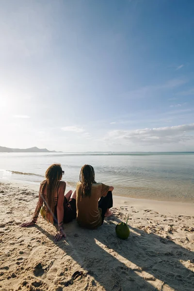 年轻夫妇坐在沙滩上 喝着椰子水 望着美丽平静的大海 — 图库照片