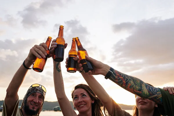 快乐的朋友们在海滩上举行聚会时 一边敬酒一边碰碰啤酒瓶 — 图库照片